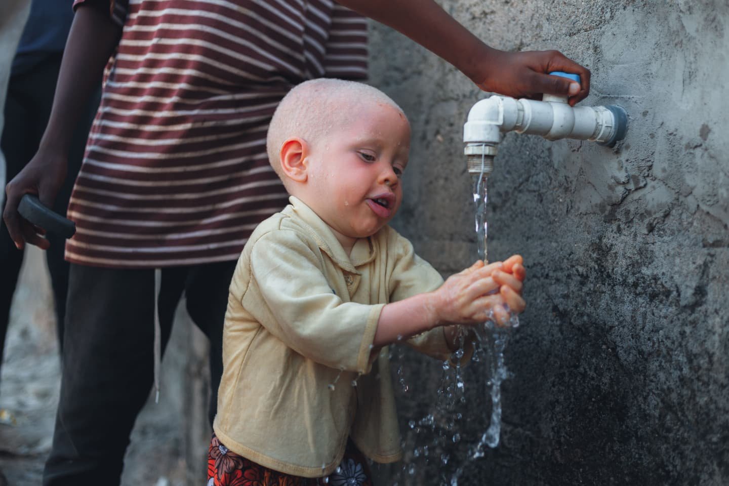 Child washing hands at a water tap