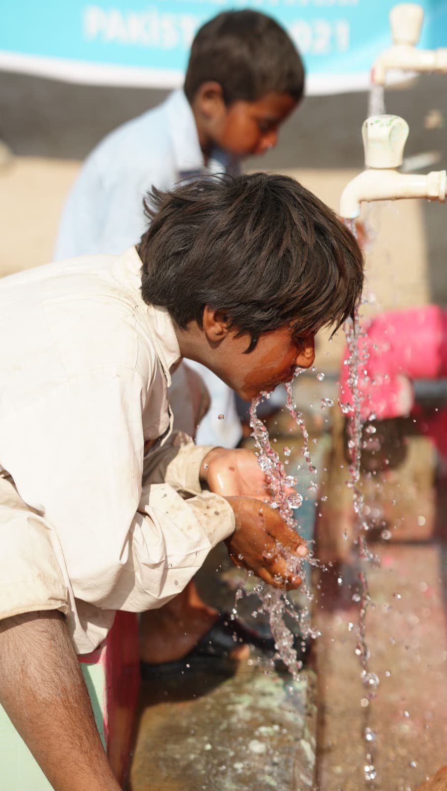 Children drinking water from community taps