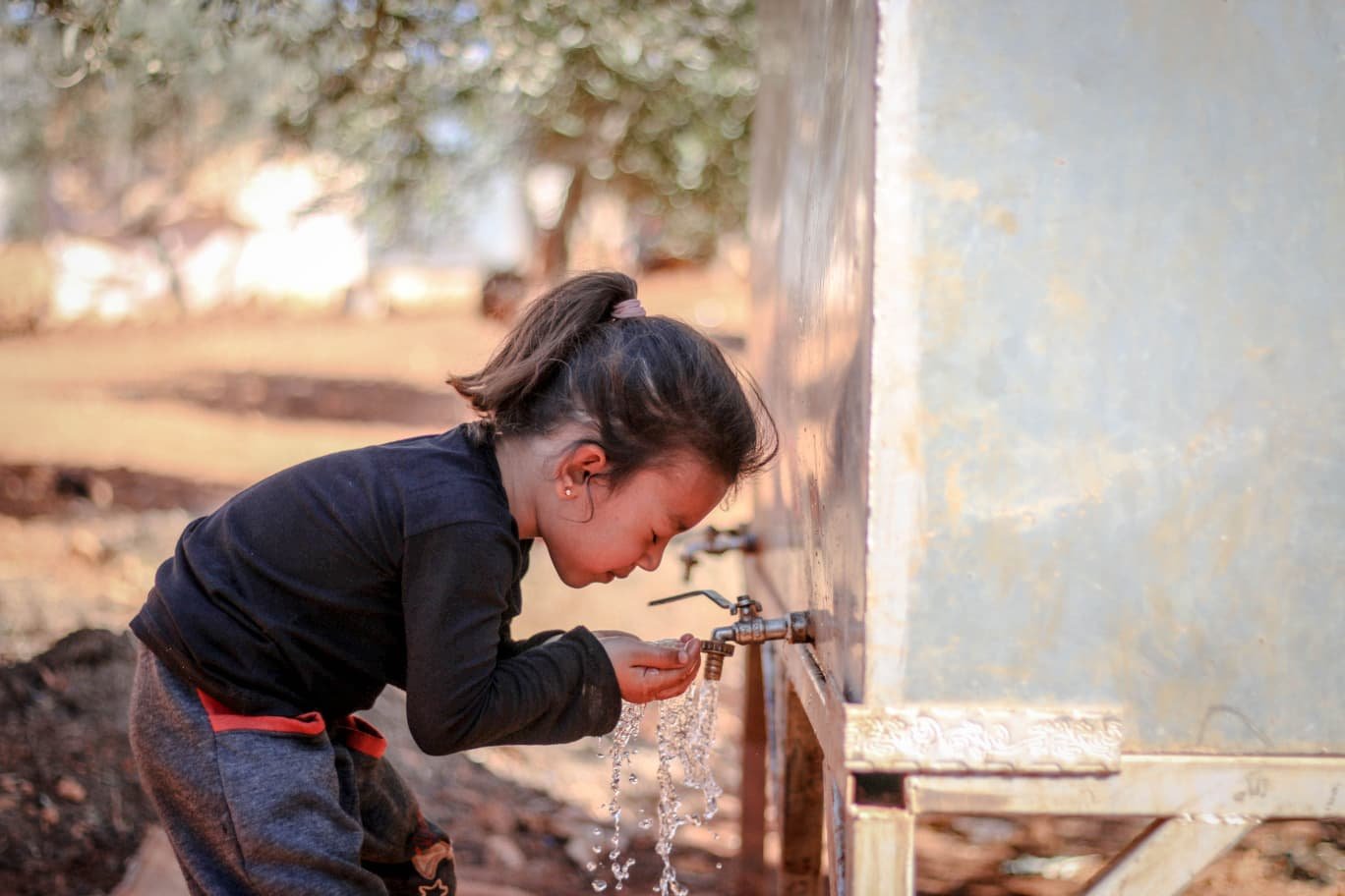 Young girl collecting clean water from a tank